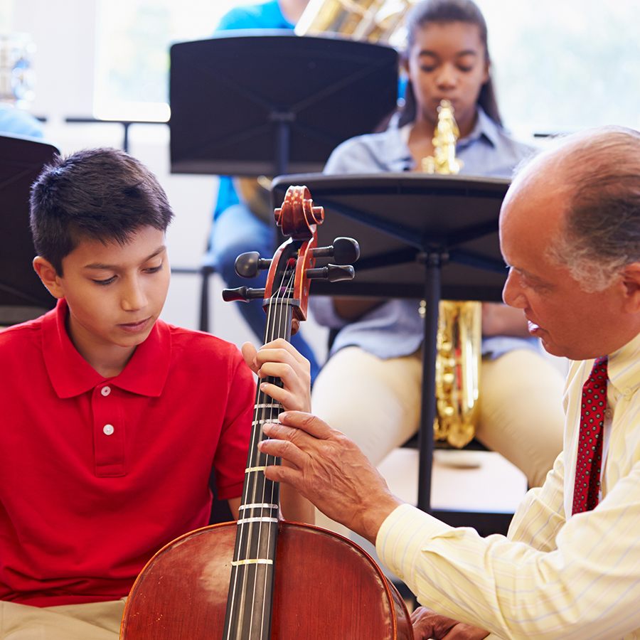 Male music instructor showing a male student fingerings on a chello