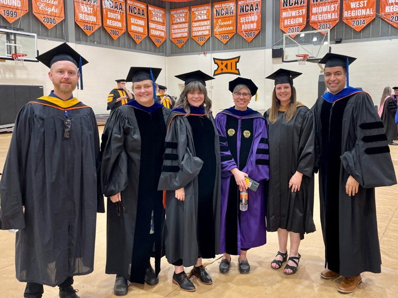 A group of people standing in graduation uniform.