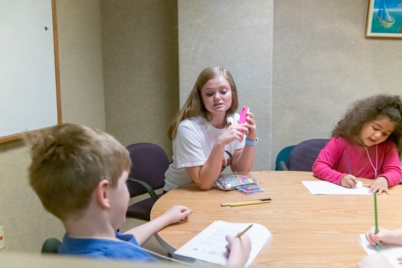 Graduate student working with children who are writing. Graduate student working with children who are writing.