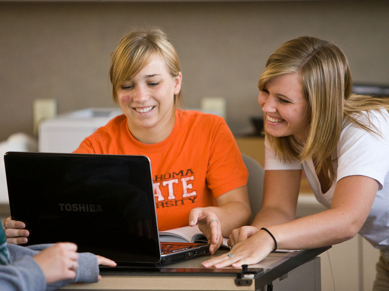 Photo of a woman helping another woman on a computer