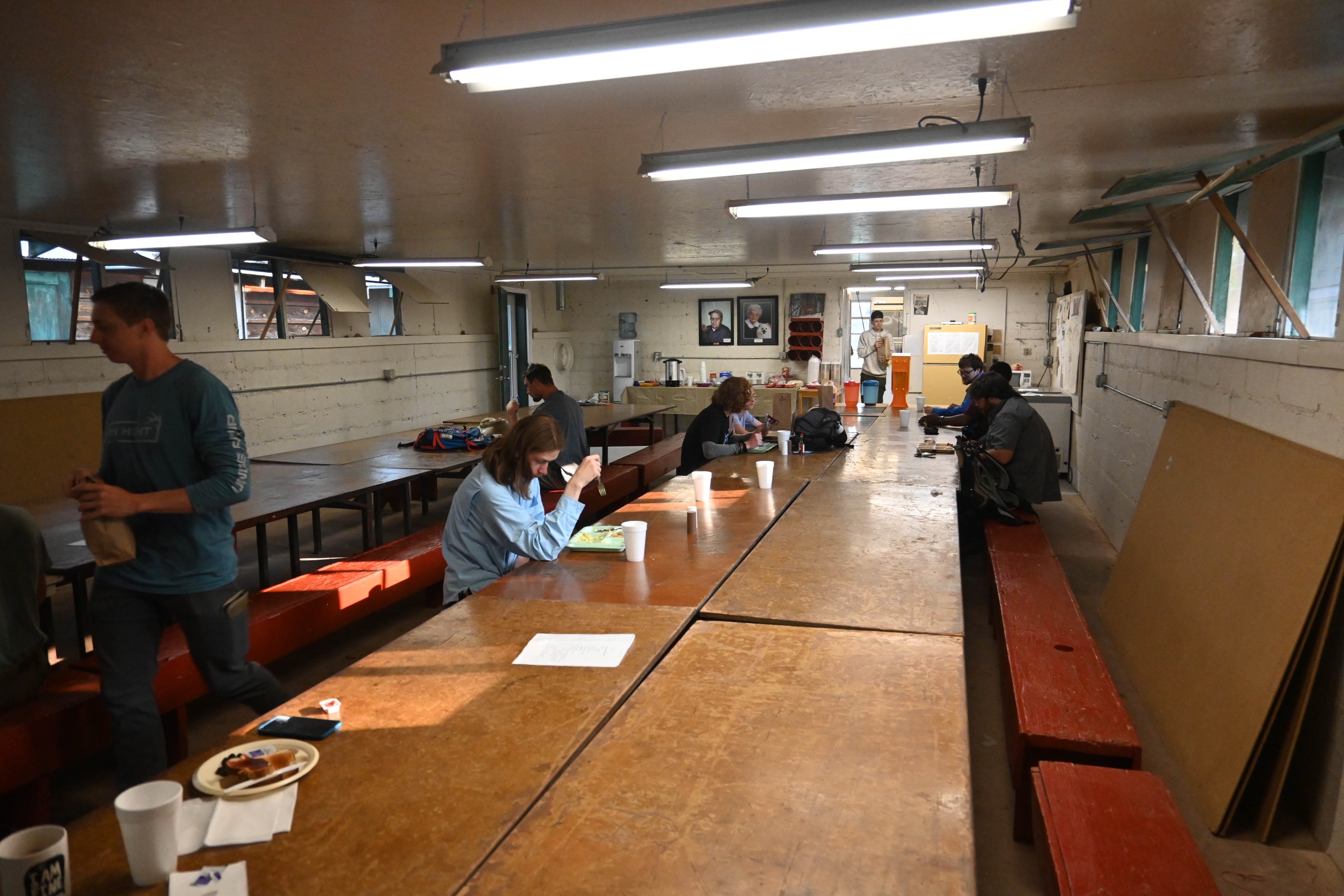 A few students eating at a long line of tables in the dining hall. A few students eating at a long line of tables in the dining hall.