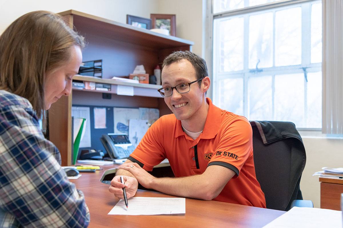Advisor sitting at desk with a student