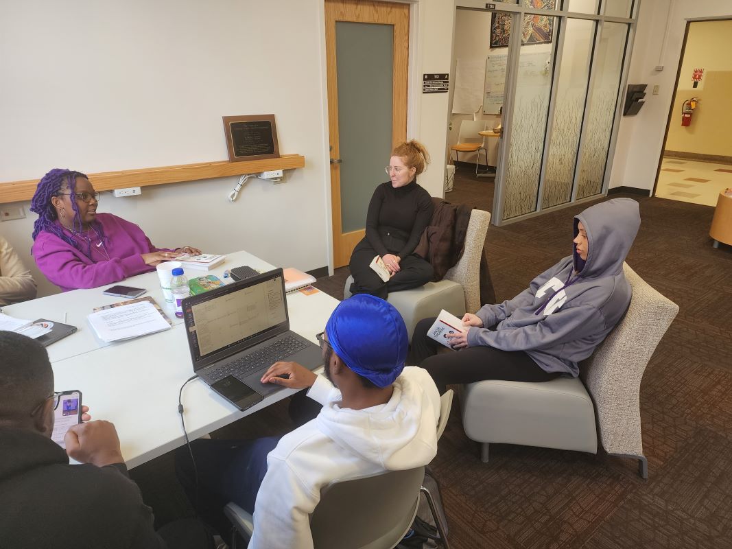 Banned Book Club: White female professor have a discussion with a group of black students.