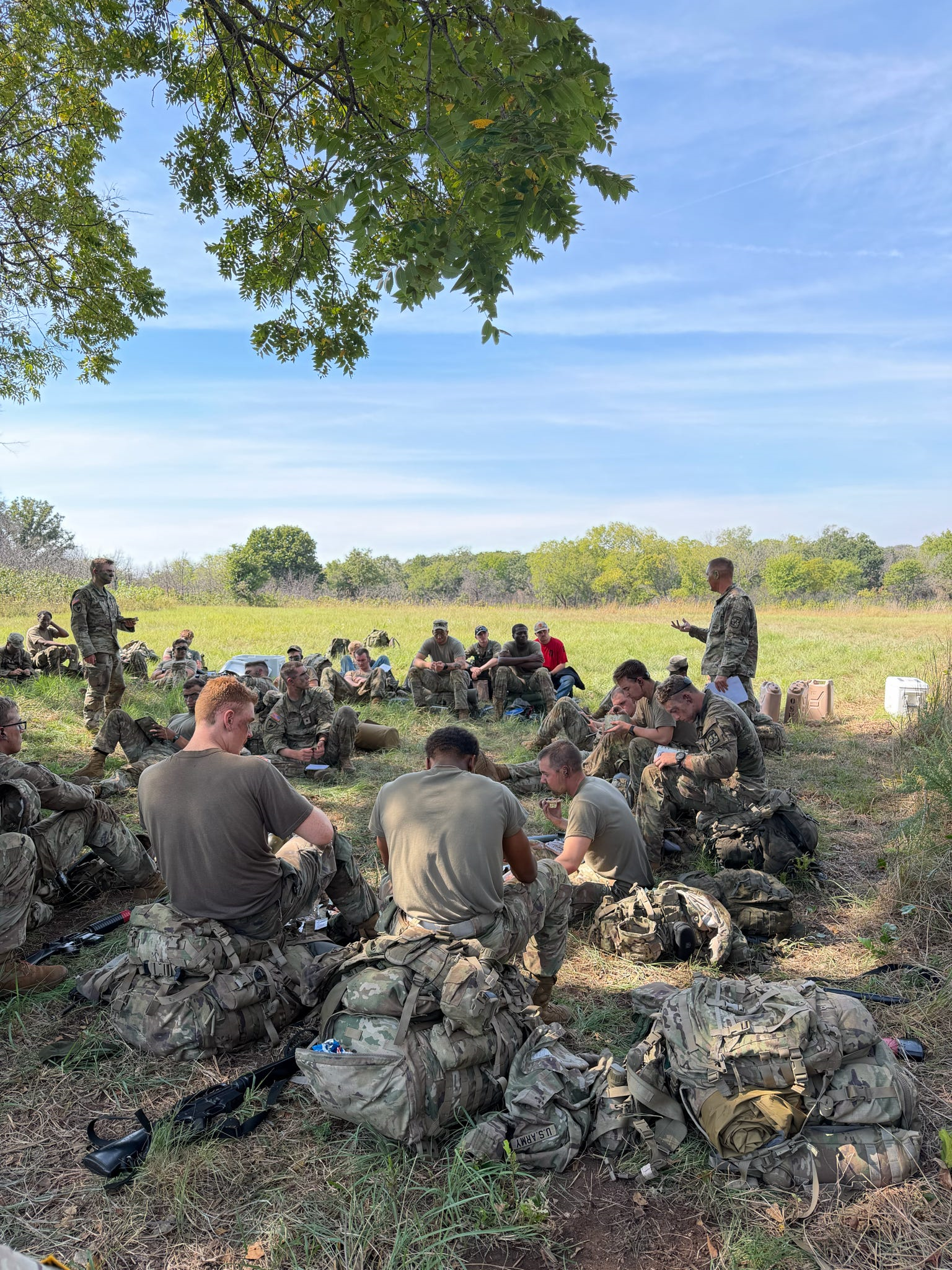 A platoon of cadets sit and work through an AAR during Fall FTX