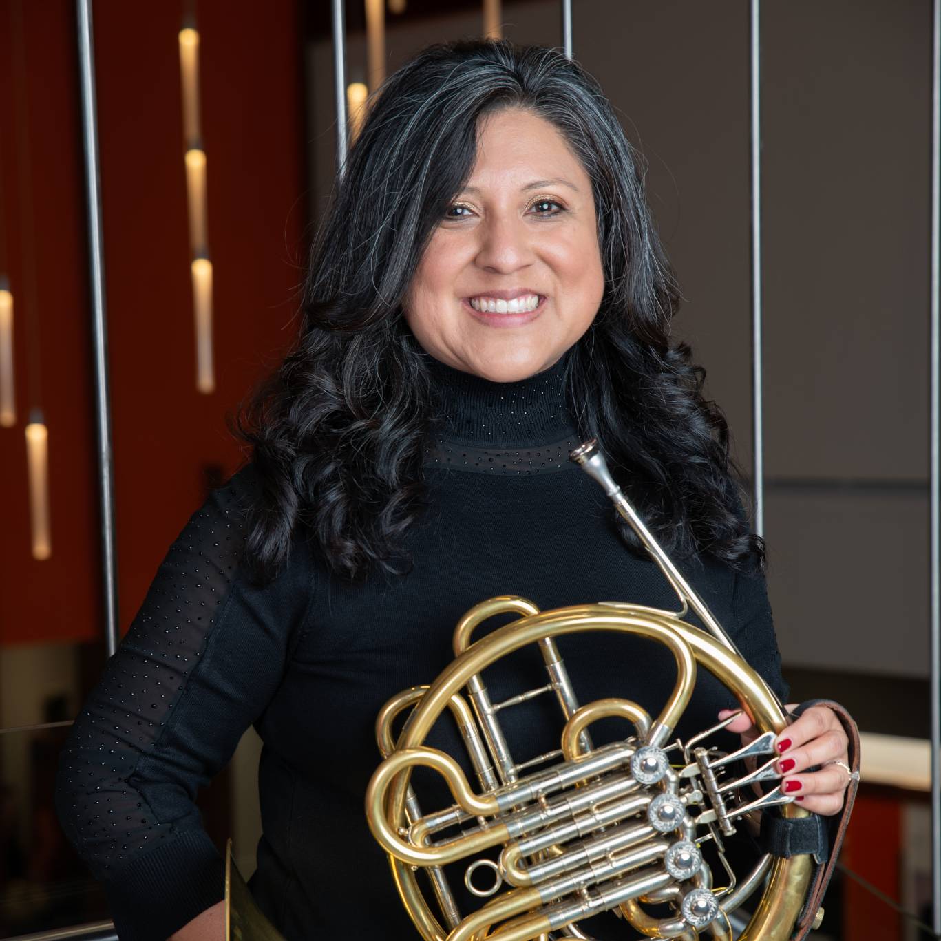 Lanette Lopez Compton wearing concert black holding her horn in front of her.