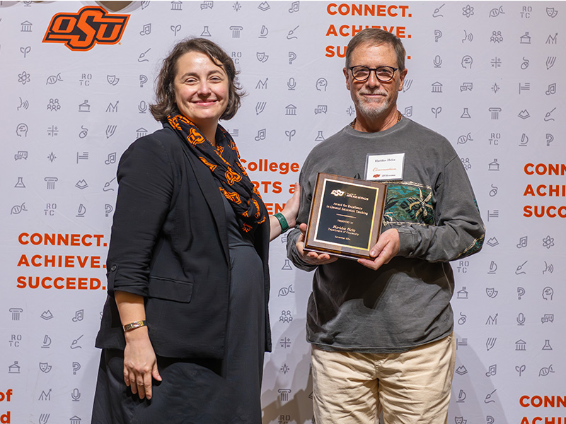 Faculty member holding a trophy while standing next to a man.