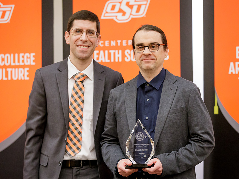 Faculty member holding a trophy while standing next to a man.