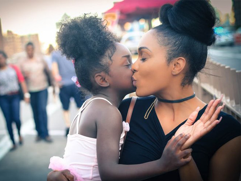 African American mother and child kissing each other's cheeks