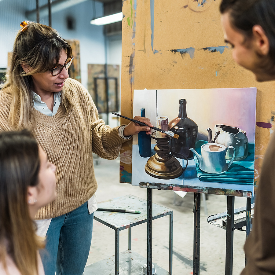 Female art instructor demonstrating to a male and female student