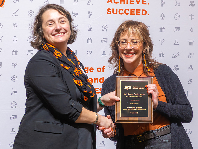 Early Career Faculty Award winner Winner Rosemary Avance holding her award on stage with Dean Cro