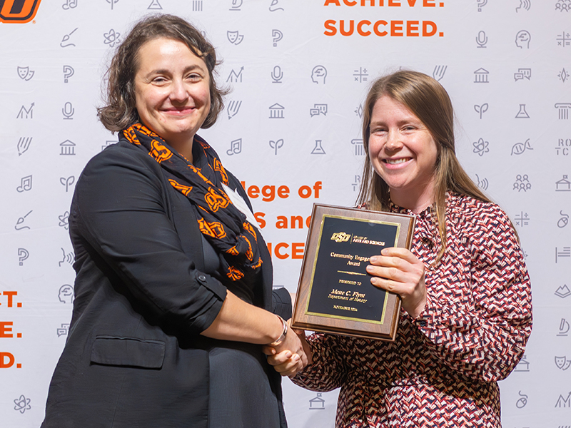 Award winner Mette Flynt holding her plaque on stage with Dean Cro