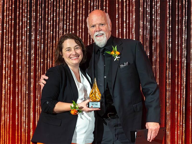 The Dean of the College of Arts and Sciences poses for a photo with actor Rex Linn at the Hall of Fame ceremony, smiling together in front of a display or banner celebrating the event.