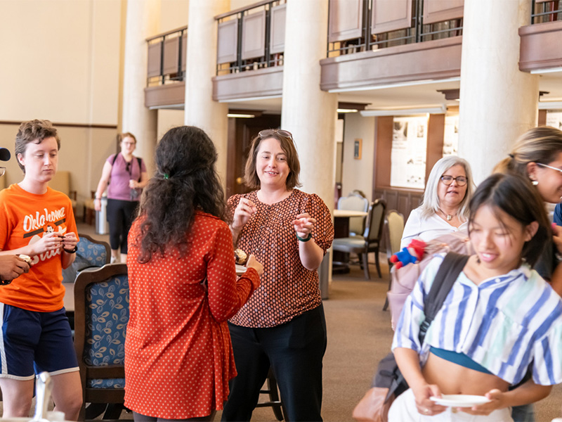 The dean celebrates with a cupcake, smiling as they hold the treats