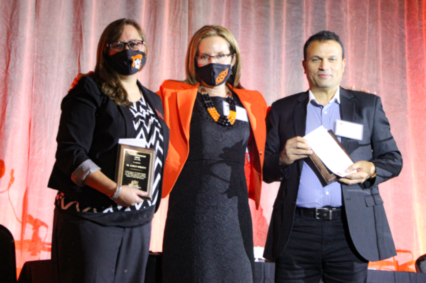 Dr. Ashley Burkett, Dr. Camelia Knapp and Dr. Ahmed Ismail posing on stage for a group photo.