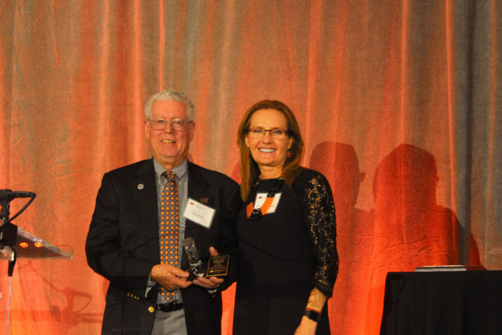 Mr. Gary Ford and Dr. Camelia Knapp posing together on stage for a photo.