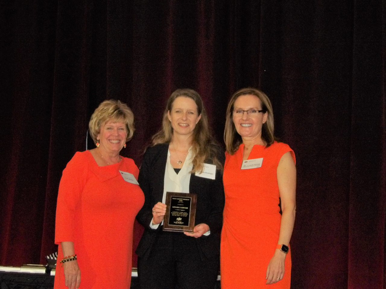 Mrs. Patty Walker and Dr. Camelia Knapp giving an award to Dr. Natascha Riedinger.