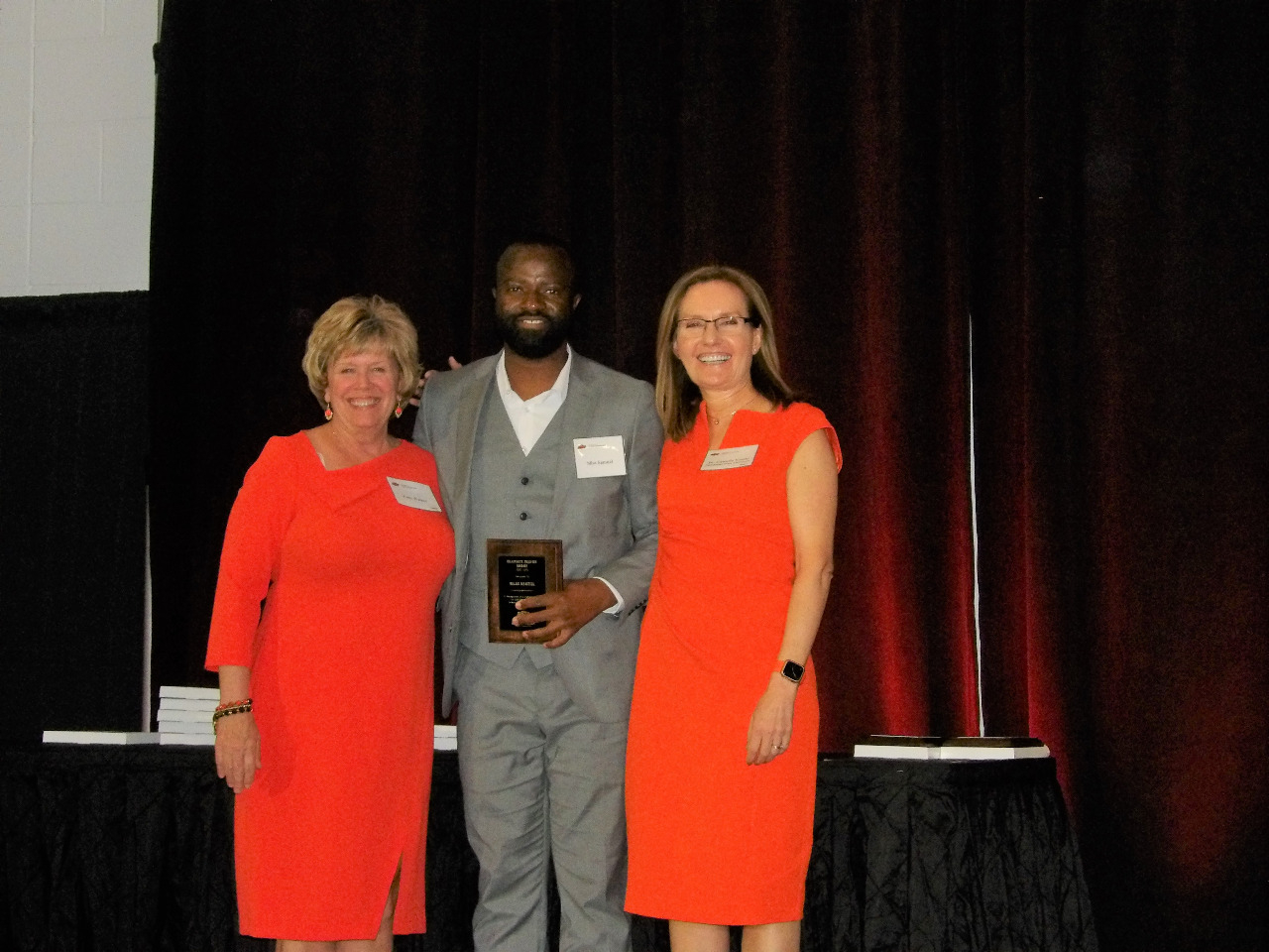 Mrs. Patty Walker and Dr. Camelia Knapp giving an award to Mr. Silas Samuel.