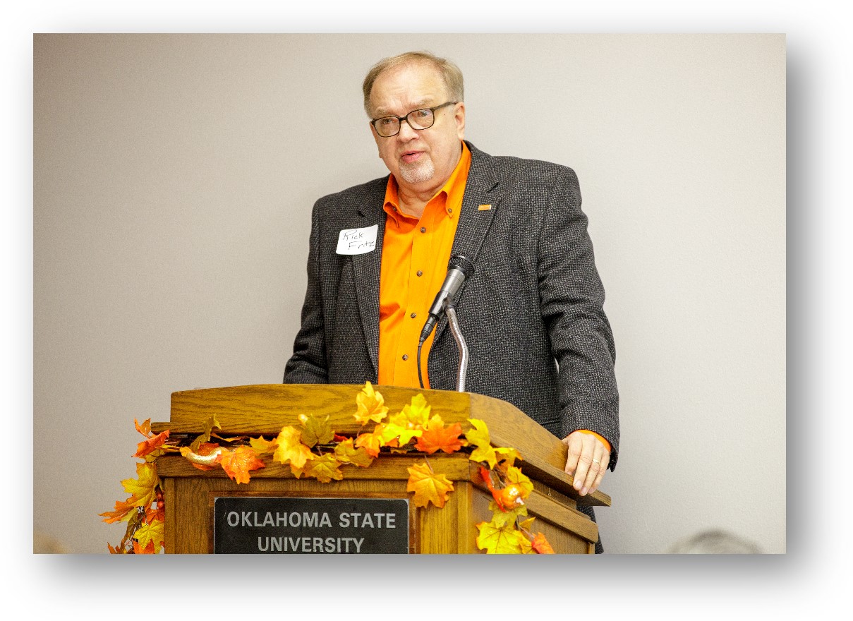 Rick Fritz, alumni member at a podium speaking to people.