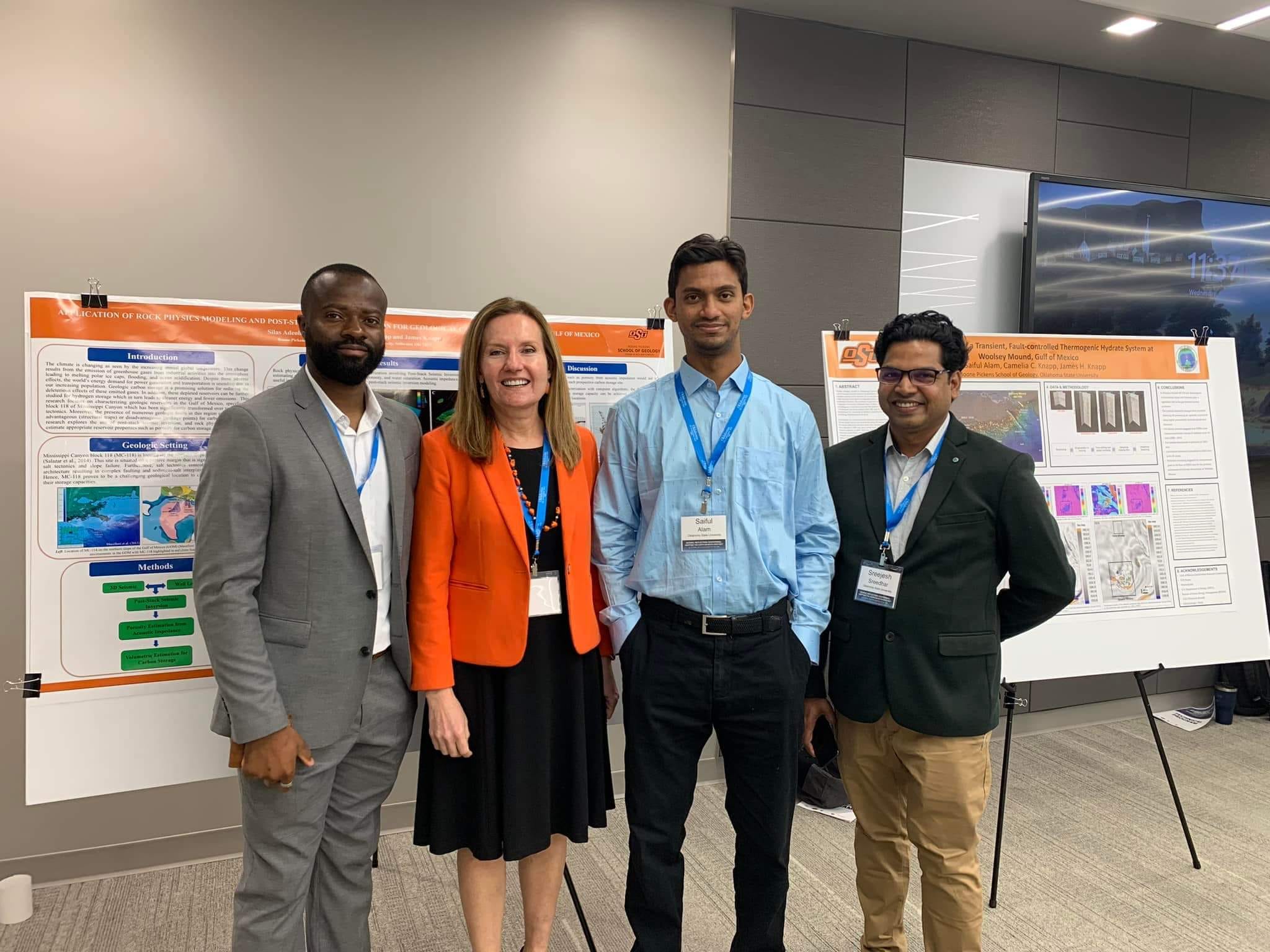 Three male students with Dr. Camelia Knapp in front of their poster presentations.