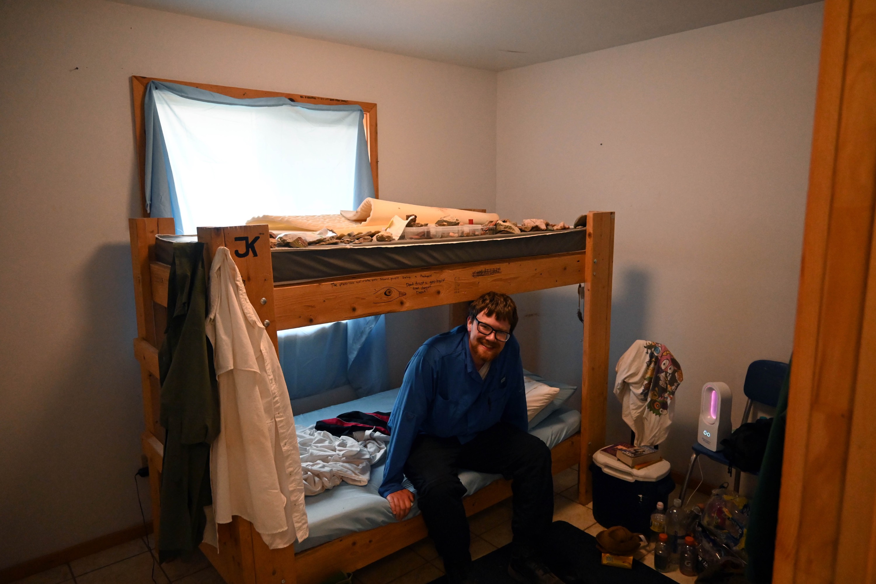 A male student sitting on the bottom bunk. A male student sitting on the bottom bunk.