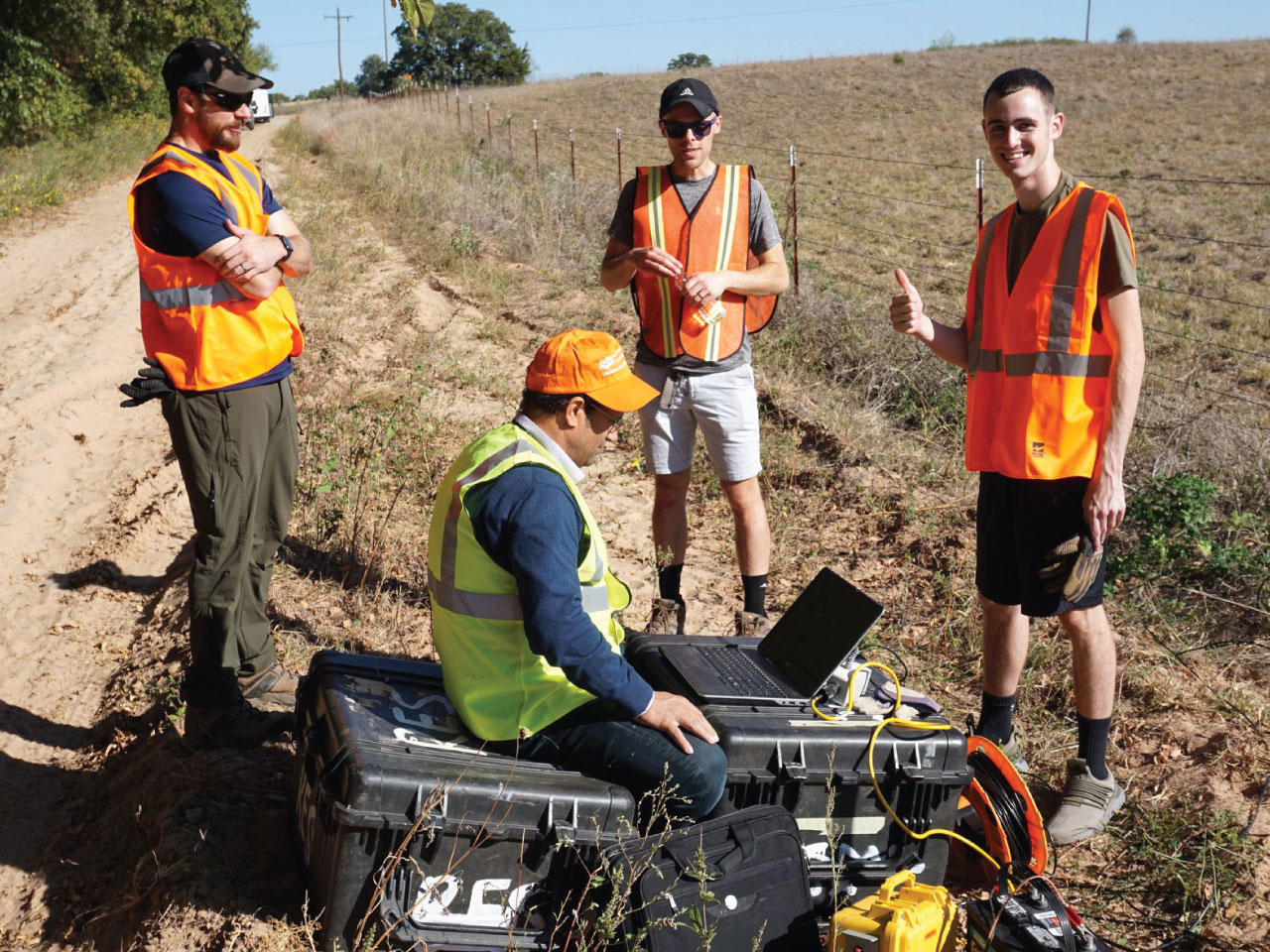 Three male students, watching Dr. Ahmed Isamil using a computer in the field. Three male students, watching Dr. Ahmed Isamil using a computer in the field.