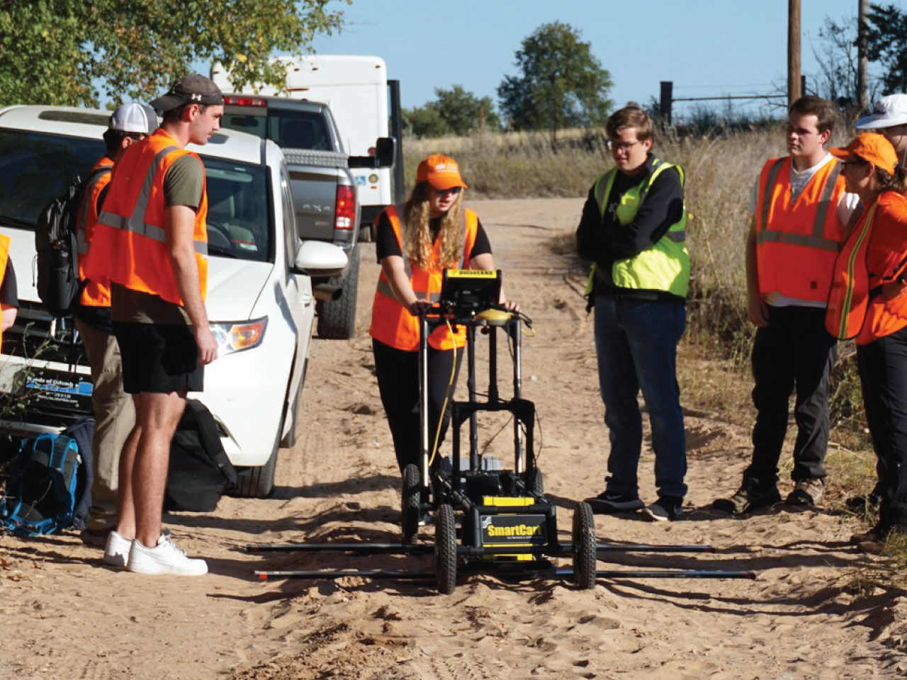 Five students watching a student use ground penetrating radar.