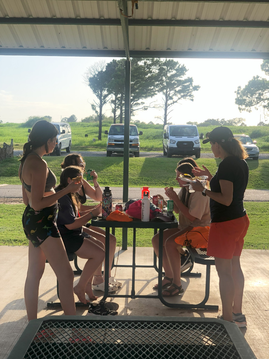 Six female students enjoying food at the GeoRex Summer Camp BBQ at Lake Carl Blackwell.