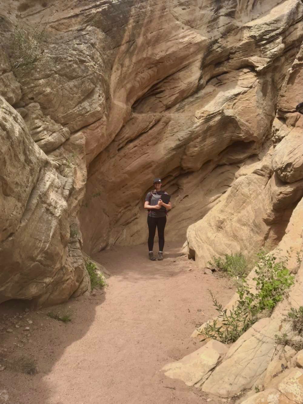 Student Chaira standing down a trail surrounded by rock formations..