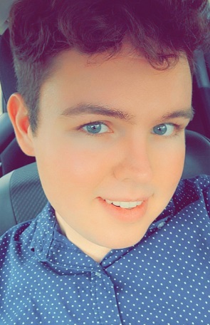 Andy Bakers has blue eyes, short hair, and wears a blue shirt.