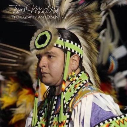 A Cherokee man in traditional regalia that is primarily green, black, and white.