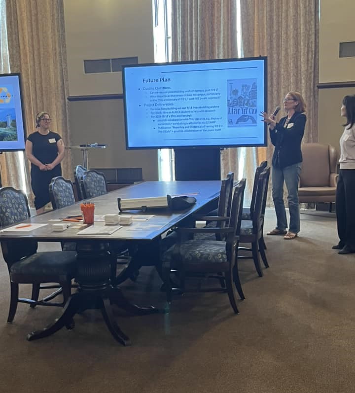 Women standing by a smartboard giving a presentation.