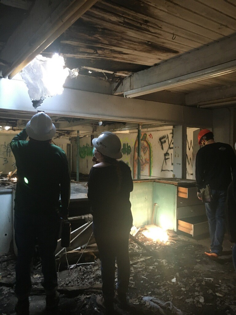 Students stand in hard hats in a dark room with grafitti on the walls.