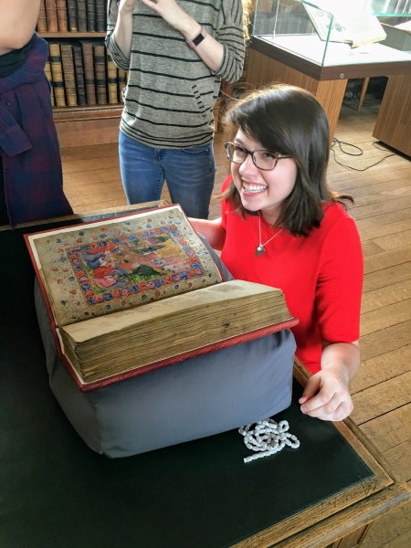 girl child smiling at a medieval manuscript