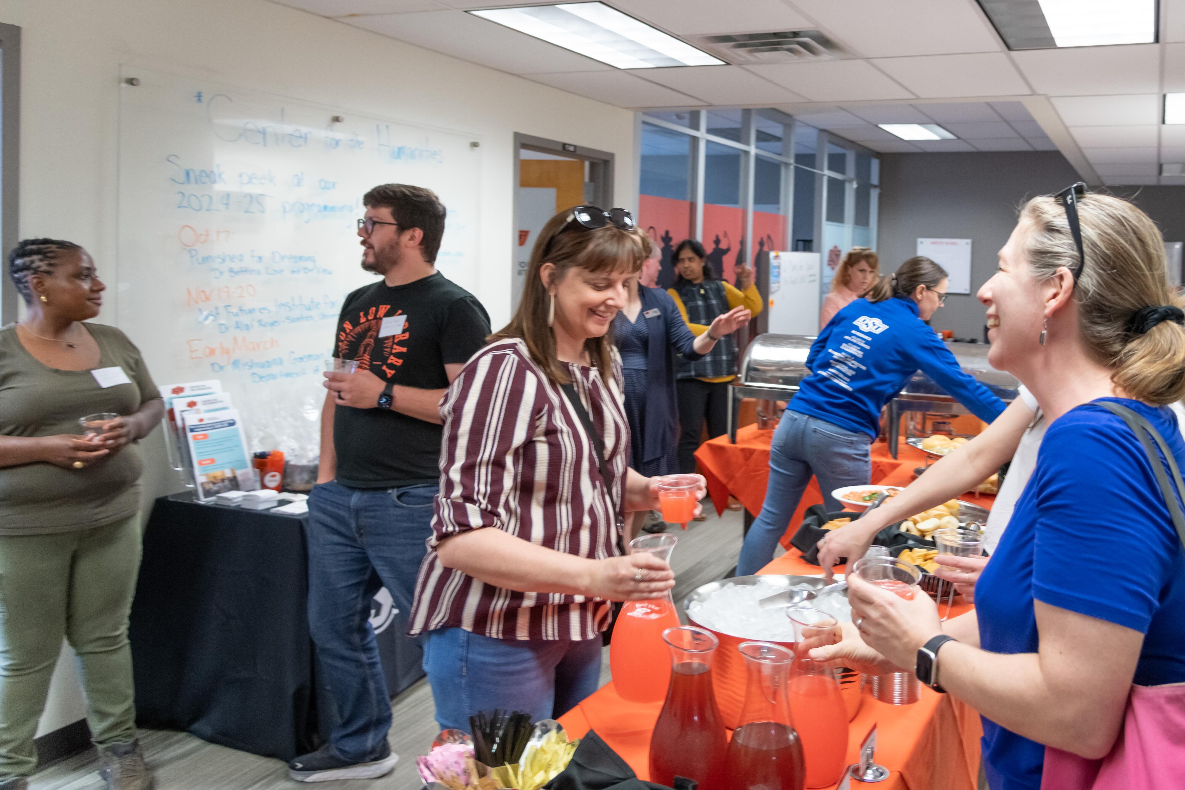 People talking and laughing in pairs with refreshments