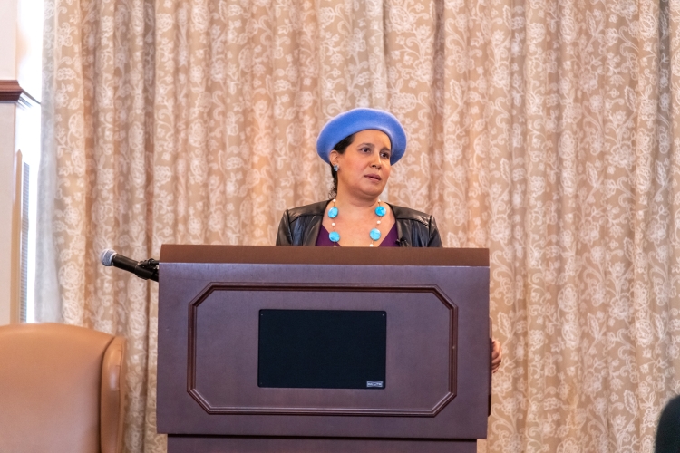 Dr. Reyes-Santos speaking at a podium. Dr. Reyes-Santos speaking at a podium.