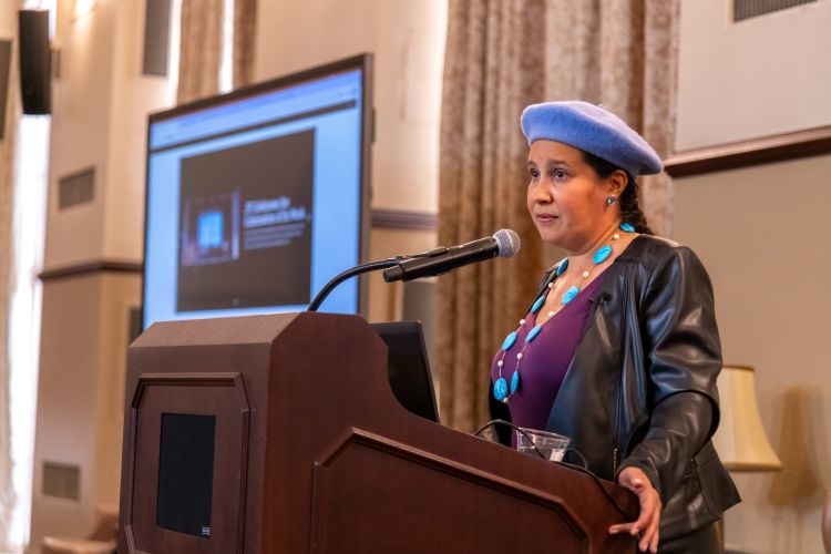 Dr. Reyes-Santos speaking at a podium. Dr. Reyes-Santos speaking at a podium.