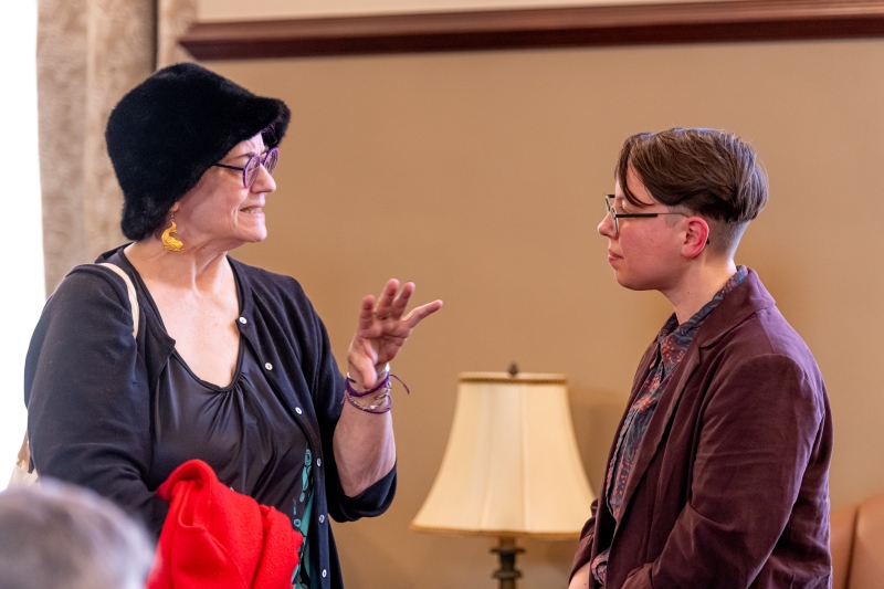 Doyle speaking with a bespectacled woman wearing a large hat Doyle speaking with a bespectacled woman wearing a large hat
