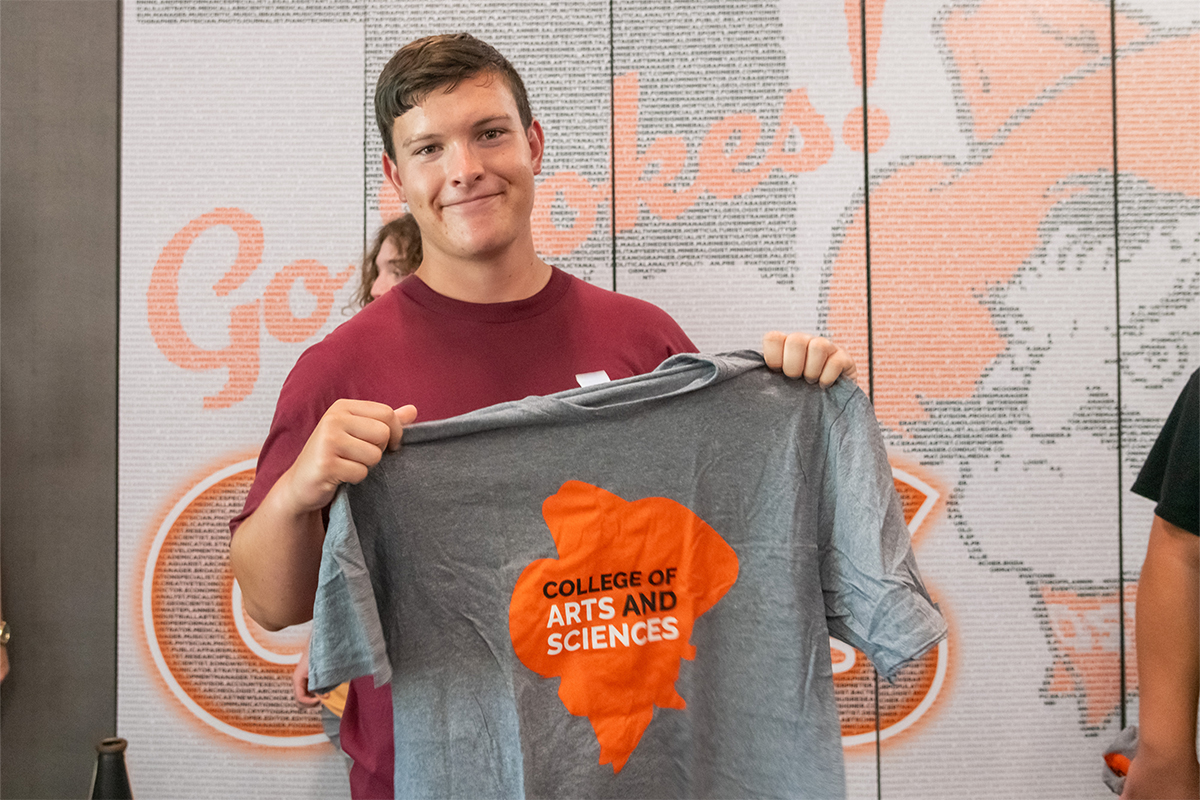 Male student holding up a CAS t-shirt