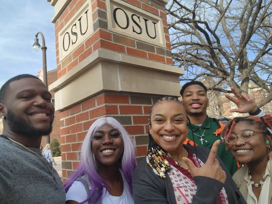 four black students and one black staffer smile infront of OSU red brick archway