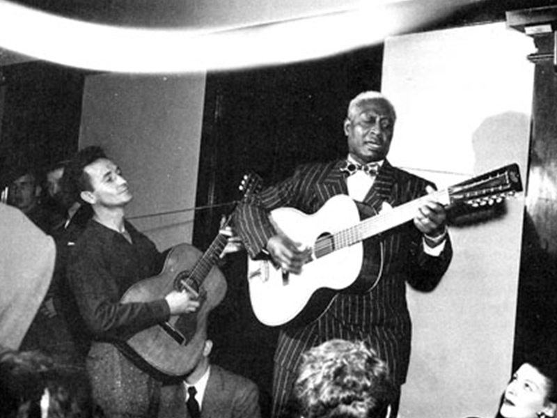 Woody Guthrie and LeadBelly playing guitars