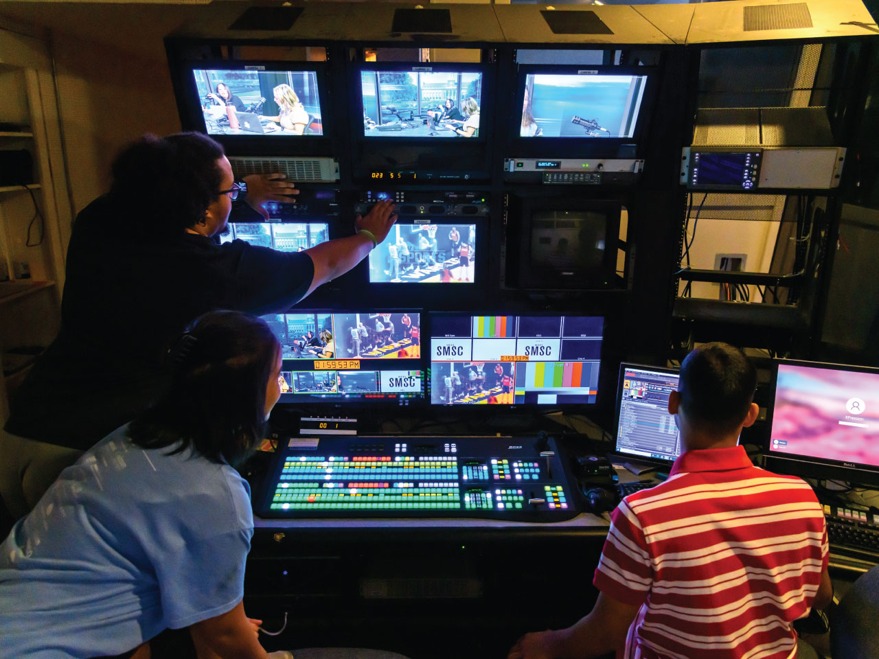 Three male students in TV control room Three male students in TV control room