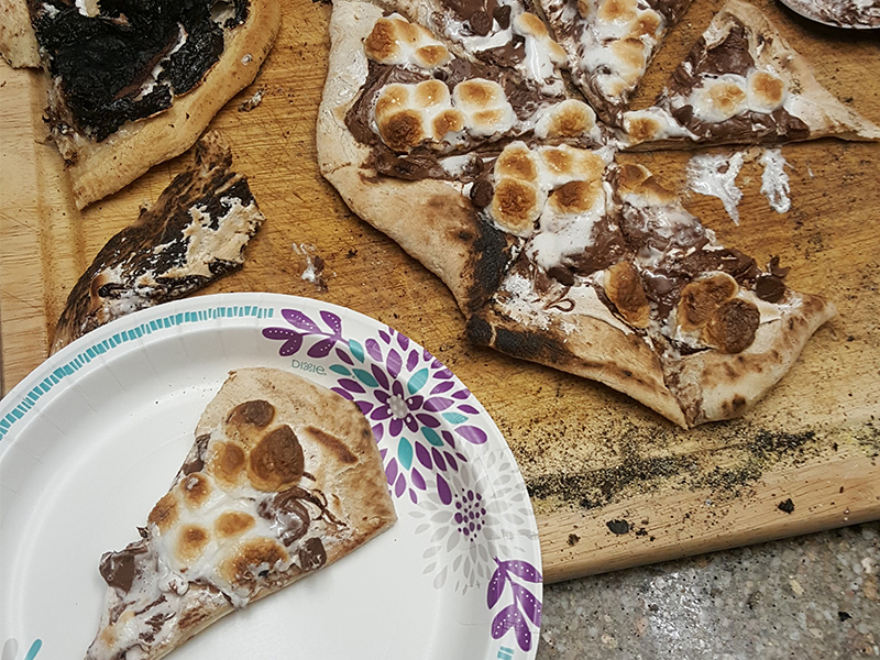 s'mores pizza with a slice on a plate