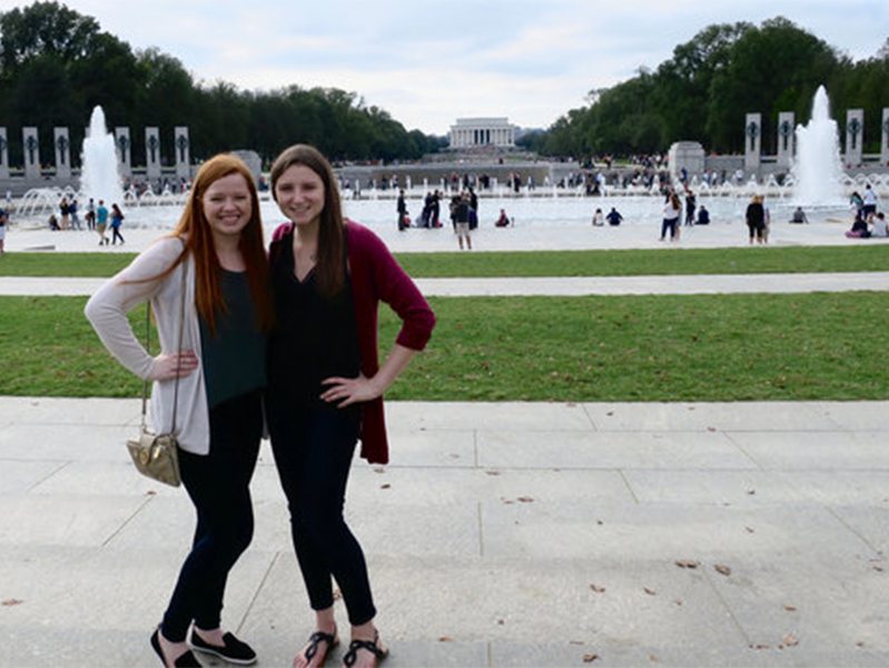 Two female students in front of a monument in Washington, D.C., at the International Society of Paediatric Oncology Conference