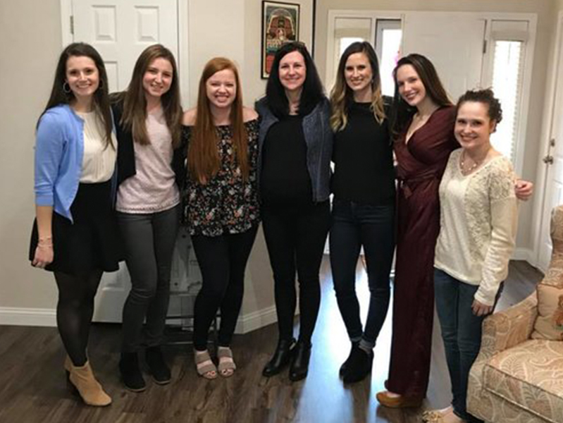 Seven female students with arms around each other smiling at camera