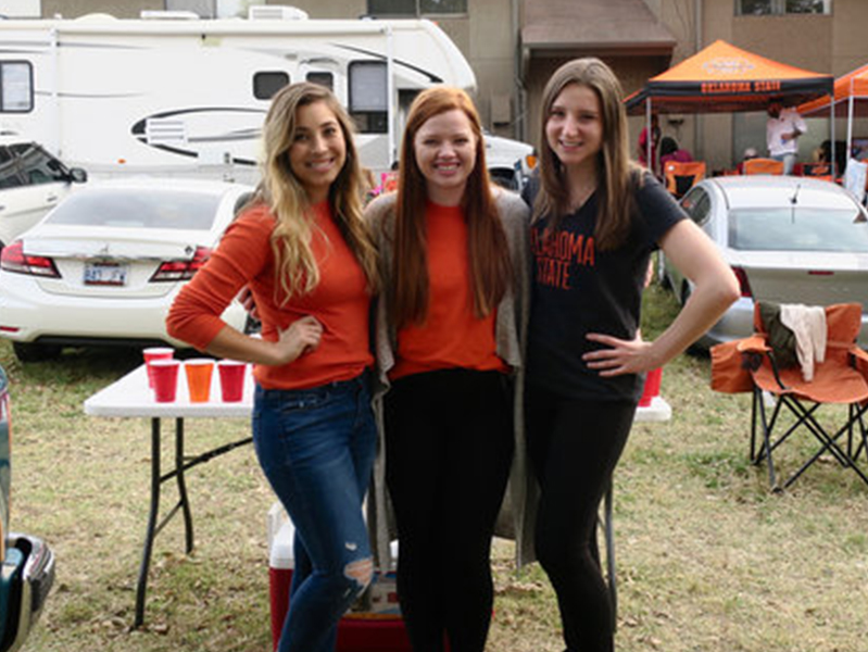 Three female students with arms around each other smiling at camera