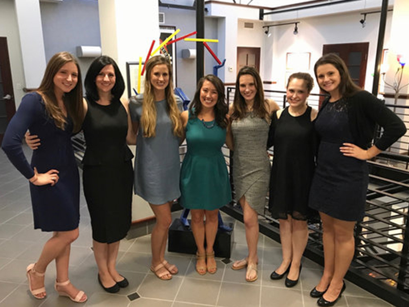Seven female students with arms around each other smiling at camera