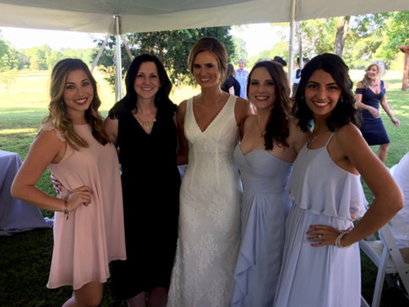 Four females around a bride with arms around each other smiling at camera
