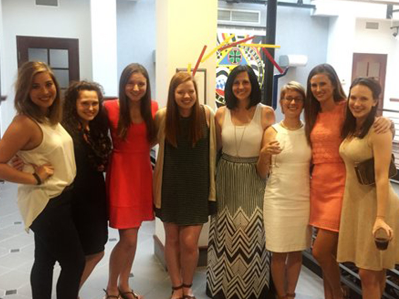 Eight female students with arms around each other smiling at camera
