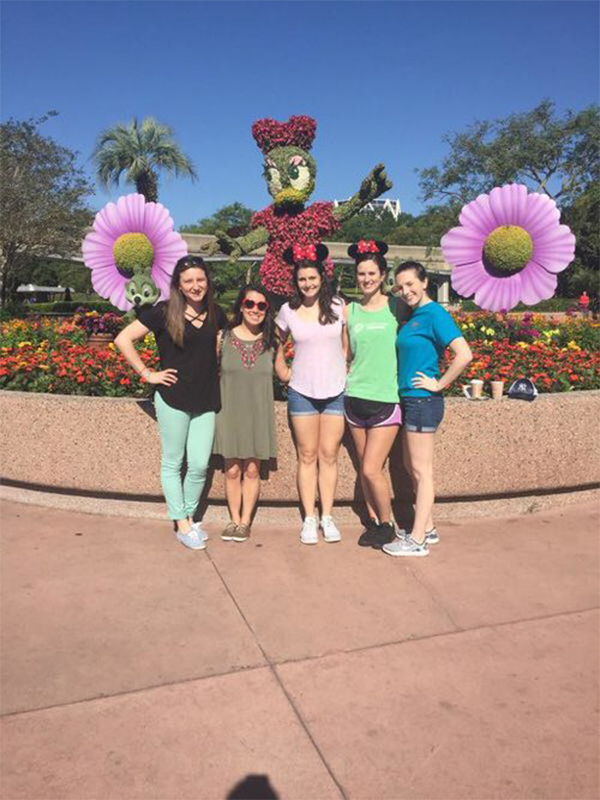 Five female students standing in front of Daisy Duck topiary at Disneyland