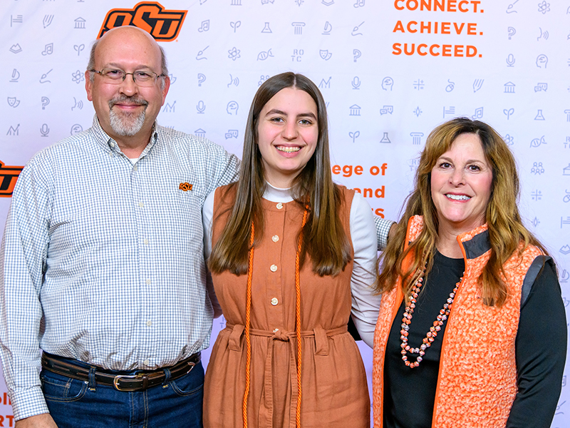 Father, Daughter and Mother smiling at camera and giving the 
